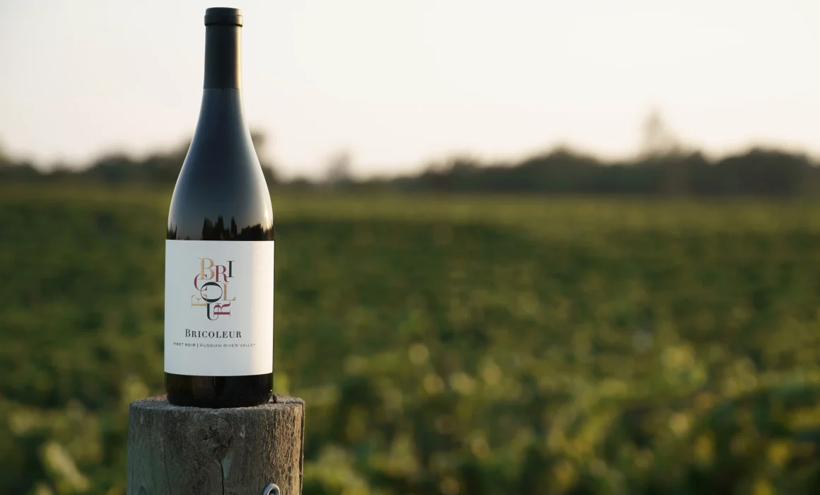 Bottle of Bricoleur Vineyards wine on top of a vineyard post