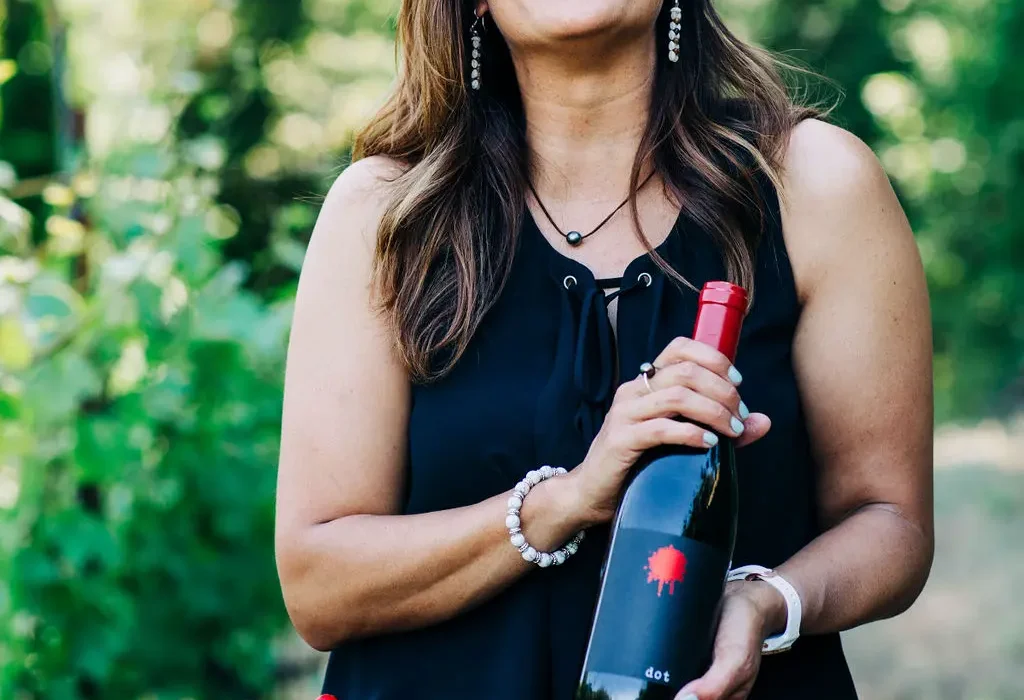 Woman holding a bottle of Dot Wine