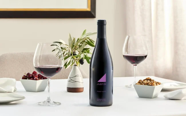 Bottle and two glasses of JUSTIN wine on a table