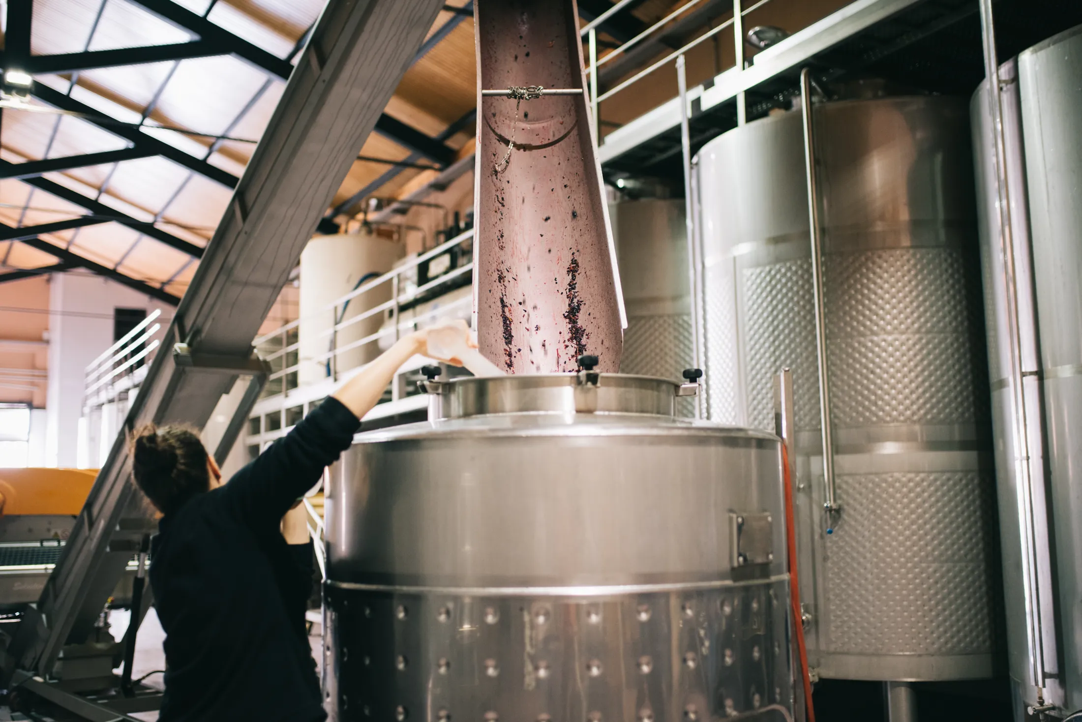 woman-working-in-a-winery-machine-2024-10-14-15-04-52-utc Woman working with a wine tank