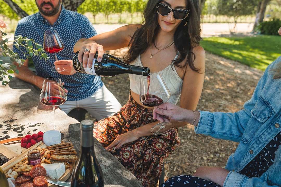 Sonya7riii Woman pouring wine for a friend over a picnic lunch